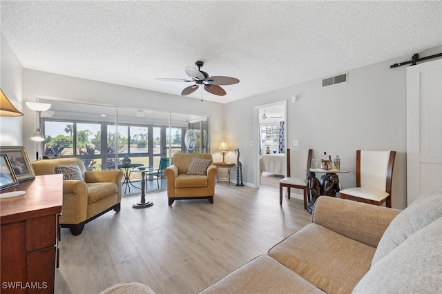 15400 River Vista Dr Unit 304, North Fort Myers, FL 33917 - living area with a barn door, ceiling fan, a textured ceiling, and visible vents
