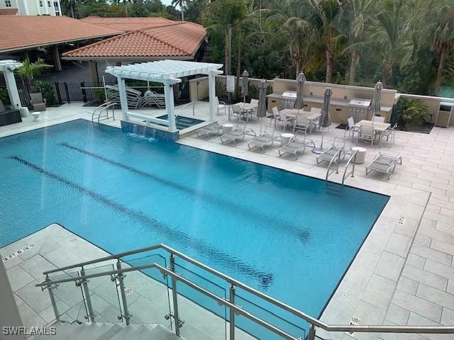 pool with exterior kitchen, a patio area, a hot tub, a pergola, and fence