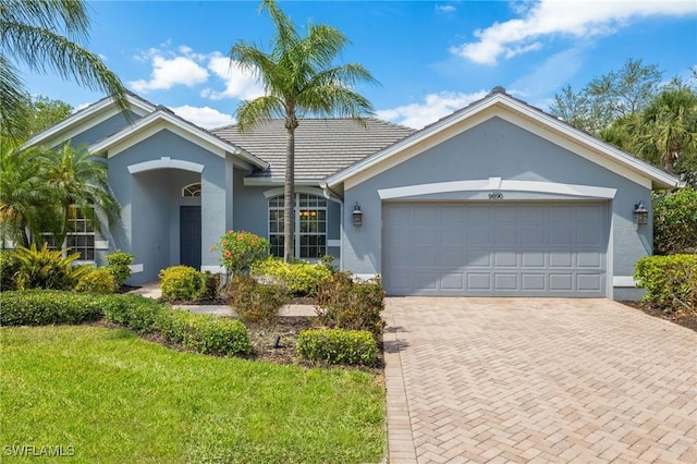 9890 Rookery Cir, Estero, FL 33928 - ranch-style house with decorative driveway, an attached garage, a front yard, and stucco siding