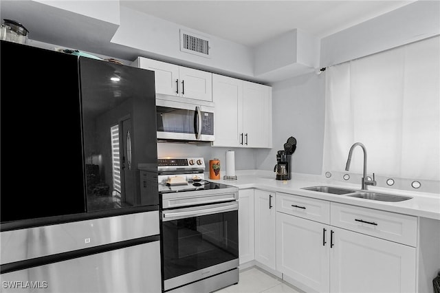 kitchen with white cabinets, a sink, appliances with stainless steel finishes, visible vents, and light tile patterned flooring