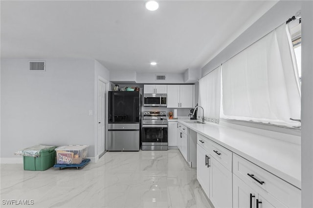 kitchen with a sink, marble finish floor, visible vents, white cabinetry, and appliances with stainless steel finishes