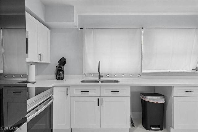 kitchen with light countertops, white cabinets, and a sink