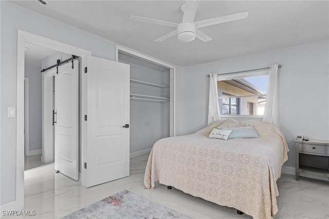 bedroom with a barn door, a closet, marble finish floor, baseboards, and a ceiling fan