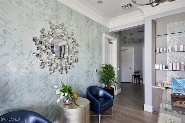 hall featuring crown molding, wallpapered walls, baseboards, dark wood-style flooring, and a notable chandelier