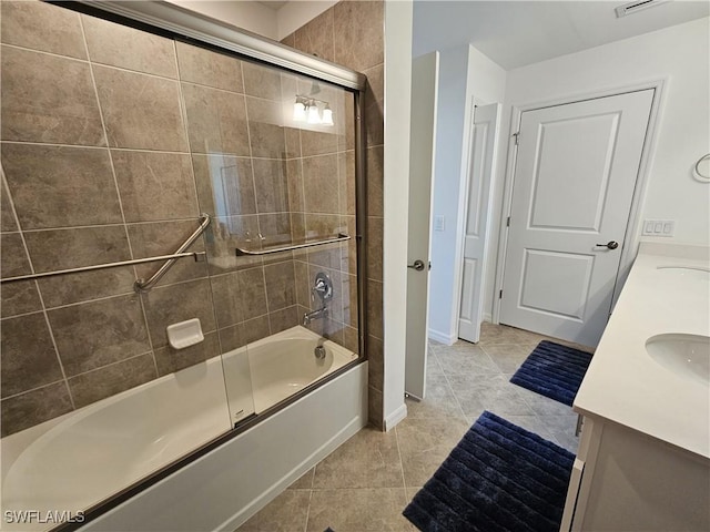 bathroom with a sink, combined bath / shower with glass door, double vanity, baseboards, and tile patterned flooring