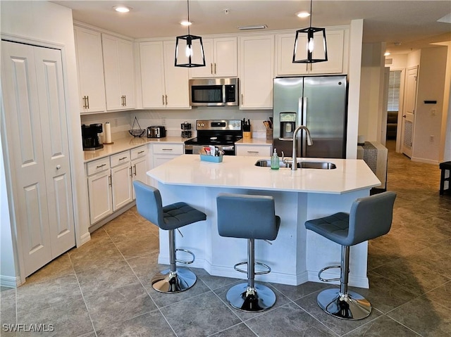 kitchen with a breakfast bar, stainless steel appliances, white cabinets, and a sink