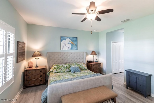 bedroom featuring ceiling fan, visible vents, wood finished floors, baseboards, and a closet