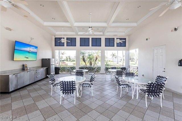 dining space with ceiling fan, a high ceiling, beam ceiling, and coffered ceiling
