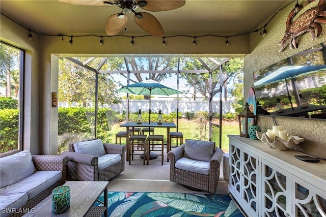 view of patio featuring glass enclosure, outdoor lounge area, a ceiling fan, and outdoor dining area