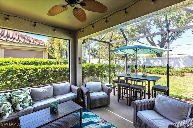 sunroom with a ceiling fan, a wealth of natural light, and an outdoor hangout area