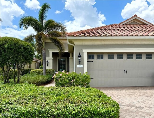 mediterranean / spanish-style house with an attached garage, driveway, a tile roof, and stucco siding
