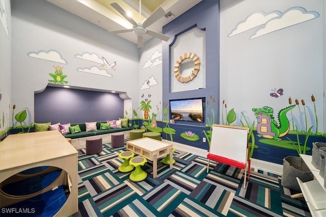playroom featuring visible vents, carpet, ceiling fan, and a towering ceiling