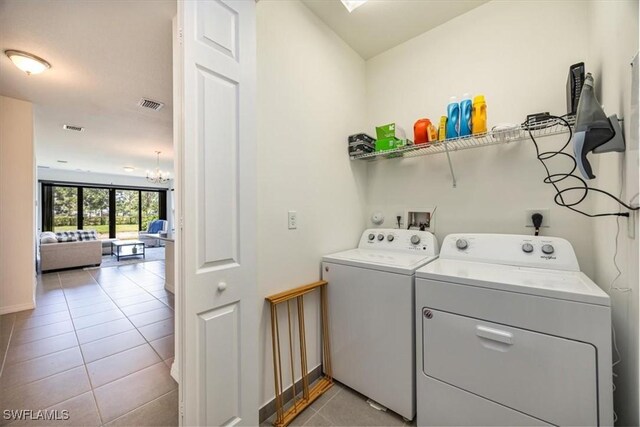 washroom with light tile patterned floors, an inviting chandelier, visible vents, and washer and dryer