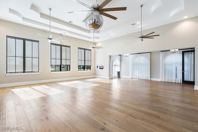 unfurnished living room with recessed lighting, a tray ceiling, a ceiling fan, and wood finished floors
