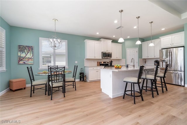 kitchen with visible vents, light wood-style floors, white cabinets, a notable chandelier, and stainless steel appliances