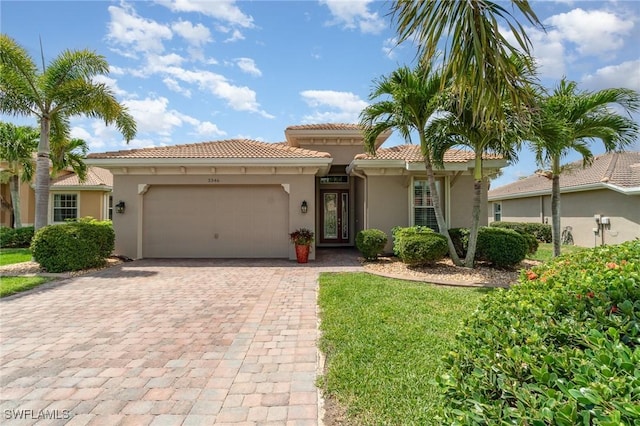 mediterranean / spanish house with decorative driveway, a garage, stucco siding, and a tiled roof