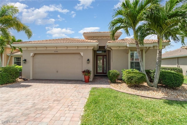 mediterranean / spanish-style home with an attached garage, decorative driveway, stucco siding, and a tiled roof