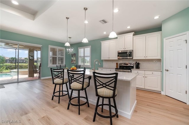 kitchen with visible vents, appliances with stainless steel finishes, tasteful backsplash, light wood-style flooring, and white cabinetry