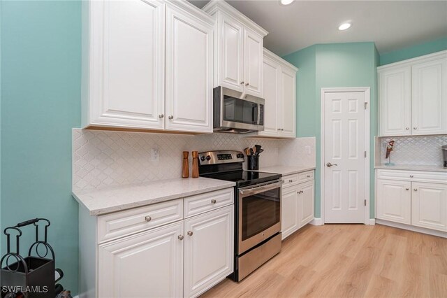 kitchen with decorative backsplash, appliances with stainless steel finishes, white cabinets, recessed lighting, and light wood-style flooring