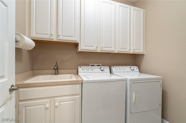 laundry room featuring cabinet space, independent washer and dryer, and a sink