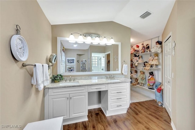bathroom featuring visible vents, a sink, lofted ceiling, and wood finished floors