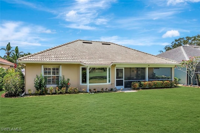 rear view of property featuring a sunroom, stucco siding, a yard, and a tile roof