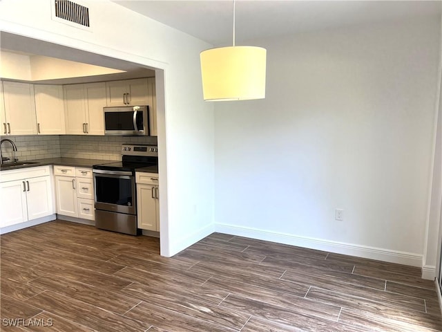 428 Meadowlark Ln Unit A, Naples, FL 34105 - kitchen featuring backsplash, appliances with stainless steel finishes, dark countertops, a sink, and baseboards