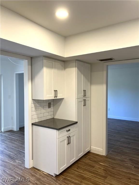 428 Meadowlark Ln Unit A, Naples, FL 34105 - kitchen featuring decorative backsplash, dark countertops, baseboards, dark wood-style floors, and white cabinetry