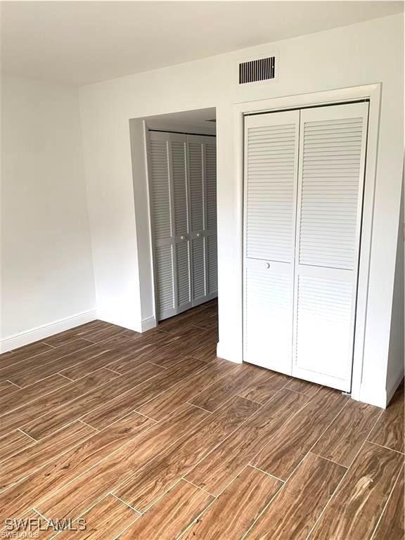 428 Meadowlark Ln Unit A, Naples, FL 34105 - unfurnished bedroom with baseboards, visible vents, wood finished floors, and a closet
