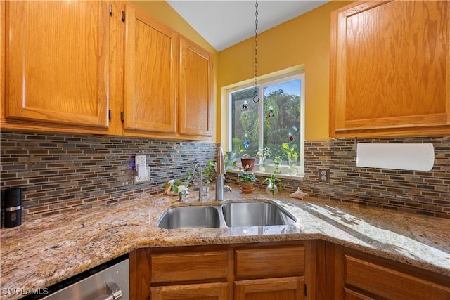 kitchen featuring light stone counters, tasteful backsplash, vaulted ceiling, and a sink