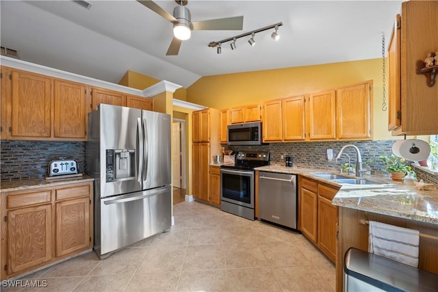 kitchen with tasteful backsplash, light tile patterned floors, appliances with stainless steel finishes, vaulted ceiling, and a sink
