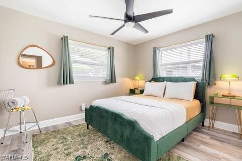 bedroom with wood finished floors, baseboards, a ceiling fan, and multiple windows