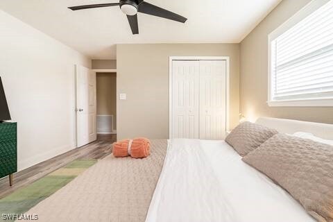 bedroom with a closet, ceiling fan, wood finished floors, and baseboards