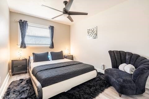 bedroom featuring baseboards, wood finished floors, and a ceiling fan
