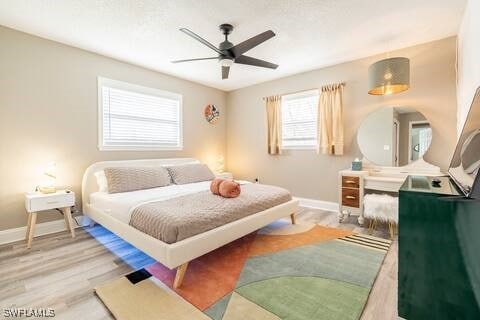 bedroom with a ceiling fan, light wood-style floors, and baseboards