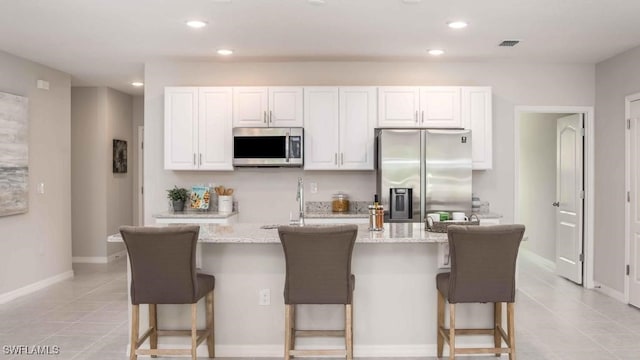 kitchen featuring light tile patterned floors, visible vents, white cabinets, and stainless steel appliances