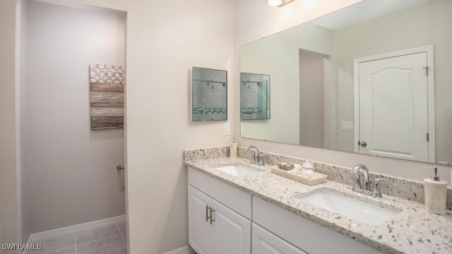 full bath featuring baseboards, tile patterned floors, double vanity, and a sink