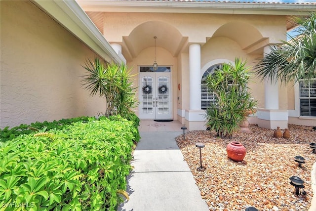 view of exterior entry with stucco siding and french doors