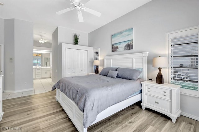 bedroom featuring a closet, light wood finished floors, baseboards, and connected bathroom