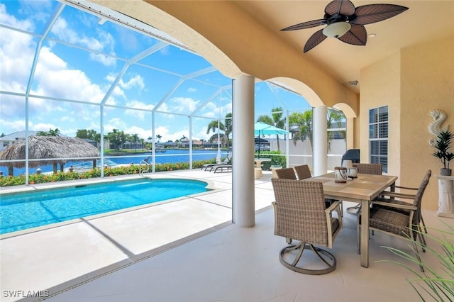 swimming pool featuring a patio area, a ceiling fan, a lanai, and a water view