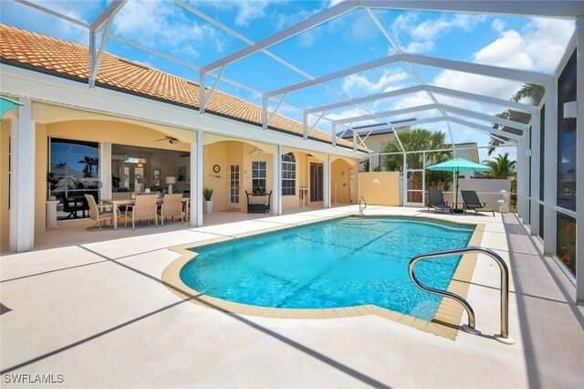 outdoor pool with a patio, a ceiling fan, and glass enclosure