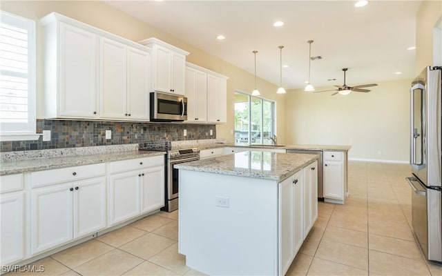 kitchen featuring appliances with stainless steel finishes, a peninsula, white cabinetry, tasteful backsplash, and recessed lighting