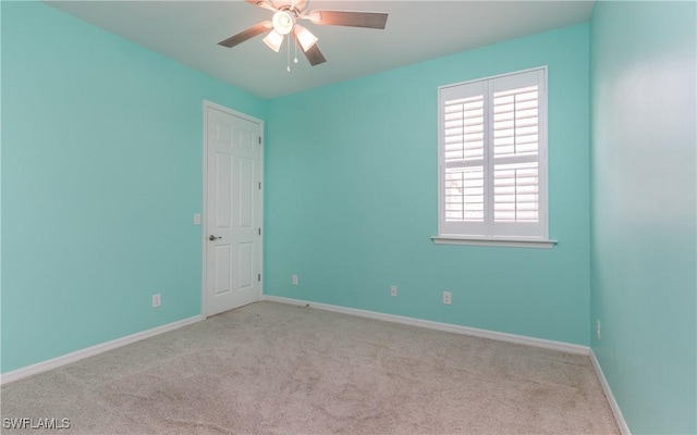 carpeted spare room with a ceiling fan and baseboards