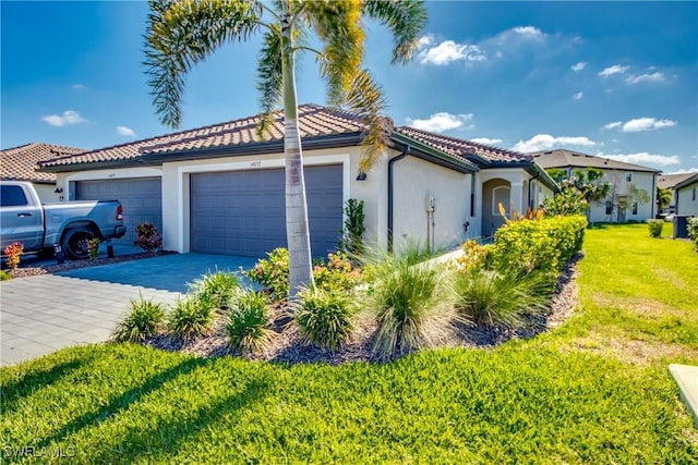 mediterranean / spanish home featuring driveway, a tile roof, a front yard, a garage, and stucco siding