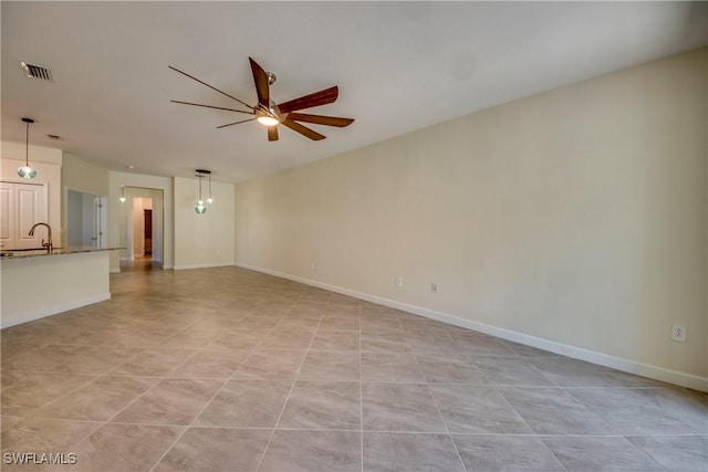 unfurnished living room featuring visible vents, a sink, baseboards, and ceiling fan