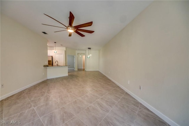 unfurnished living room featuring a sink, baseboards, ceiling fan, and light tile patterned flooring