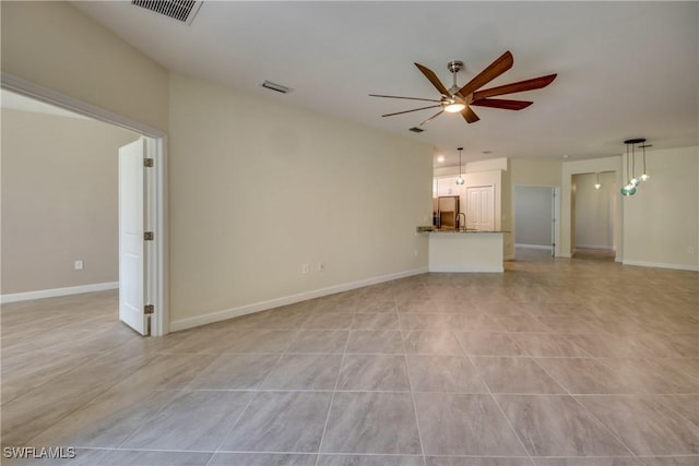 unfurnished living room with ceiling fan, visible vents, and baseboards