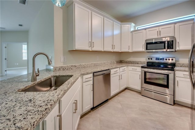 kitchen with light tile patterned flooring, appliances with stainless steel finishes, a sink, white cabinetry, and visible vents