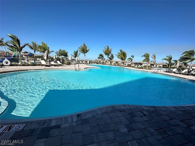 pool with a patio area and fence