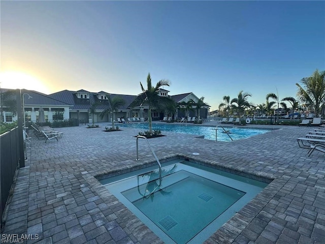 pool at dusk featuring a community pool, a patio, and fence
